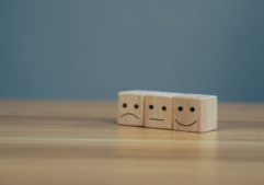 Satisfaction concept, Close up icon smiley face and blurred sad face on wood cube